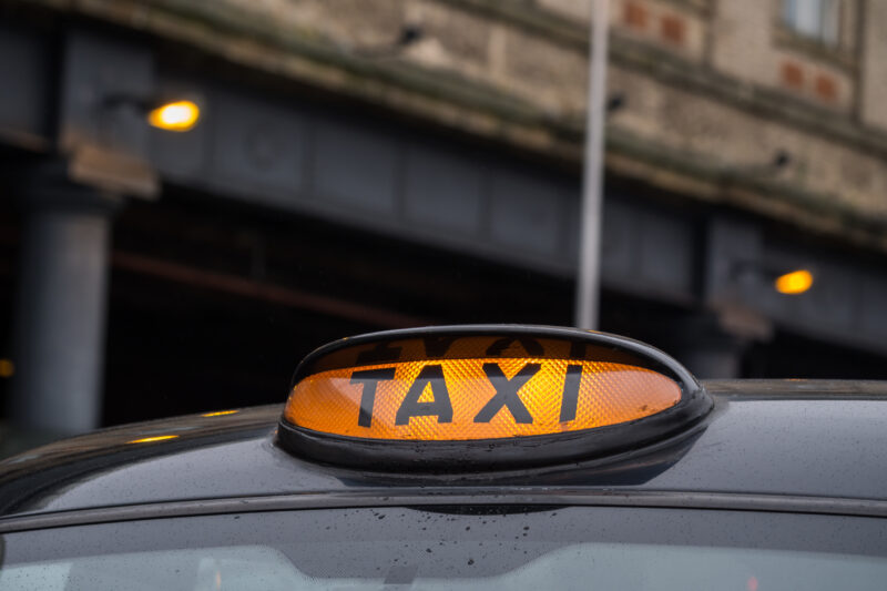 Illuminated yellow taxi sign on a typical old style black taxi in Manchester, Great Britain. Close up.