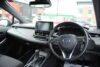 Front interior of a Toyota Corolla showing the steering wheel, sat-nav and radio.