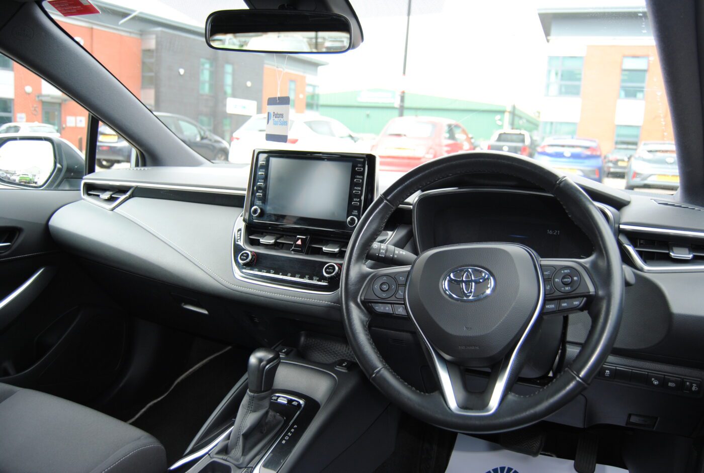 Front interior of a Toyota Corolla showing the steering wheel, sat-nav and radio.