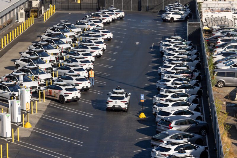 Overhead view of Waymo robotaxis in a San Francisco parking lot among other waymos.